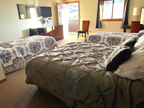 Beaver CityFurnas County Lodging的酒店客房设有两张床和电视。