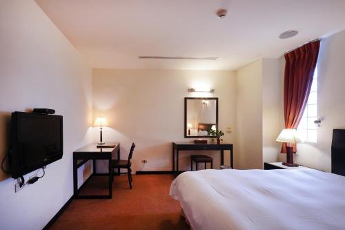 台中市禾康商务旅馆的酒店客房,配有床和电视
