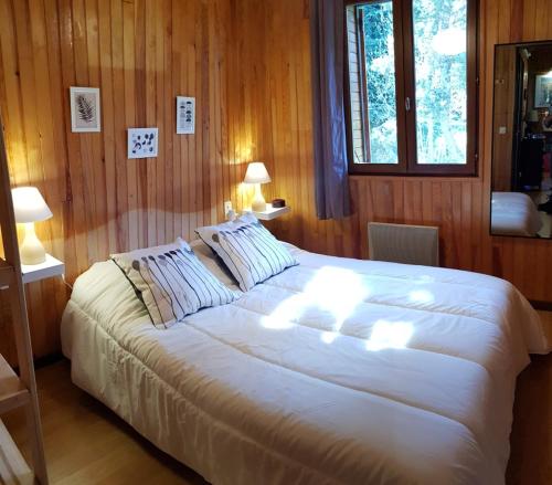 埃安Chalet La Campagnette的木制房间一张大白床,配有两盏灯