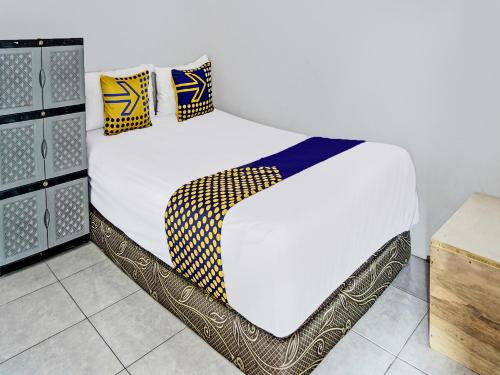 MojokertoOYO 92086 Fun Guesthouse Syariah的一张配有白色床单和黄色及蓝色枕头的床