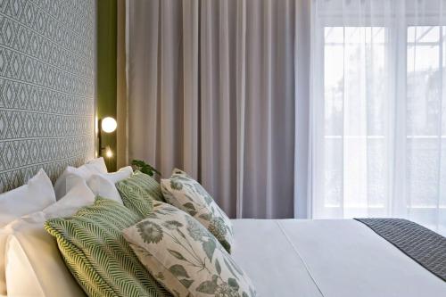 布加勒斯特Central Hotel, Trademark Collection by Wyndham的卧室配有带枕头的床铺和窗户。