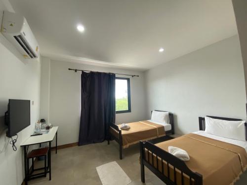 Pattani巴卡兰农场度假村的客房设有两张床、一张桌子和一个窗户。