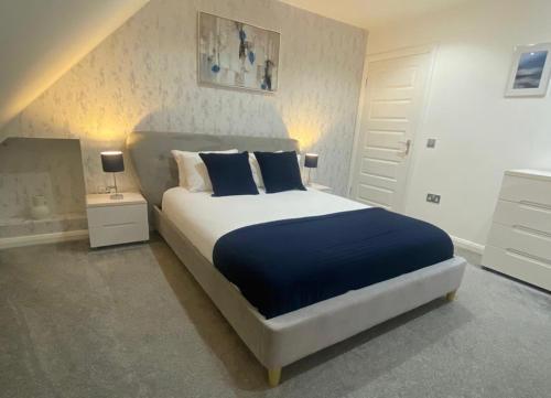 福尔柯克Alma Villa的一间卧室配有一张带蓝色枕头的大床