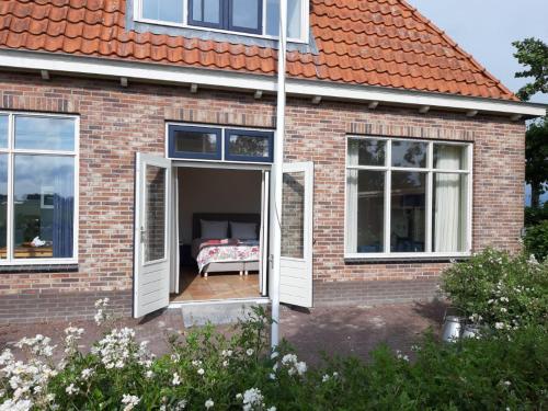 阿克伦Luxe gastenverblijf in het hart van Friesland的砖房,设有一扇开门,里面设有一张床