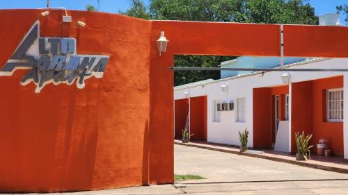 帕特拉德拉帕特拉Apart Alto Parana的一座橙色的墙,上面有标志,在建筑旁边