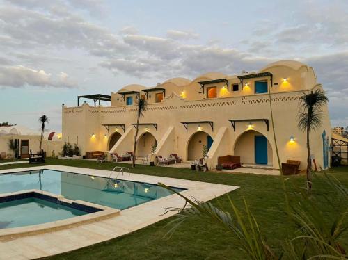 Qaryat at Ta‘mīr as SiyāḩīyahLake House by Tunisia Green Resort的一座大房子,前面设有一个游泳池