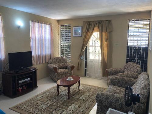 布里奇敦DonaMae 2 story Barbados House的客厅配有沙发、椅子和电视