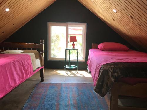 Bajo BoqueteAxelmaria的阁楼卧室设有两张床和窗户。