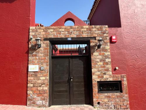 圣米格尔德阿沃纳Hotel Ecolife Tenerife的砖砌的建筑,有黑色的门和红色的墙