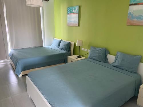 拉罗马纳Villa Real Playa Nueva Romana的绿墙客房内的两张床