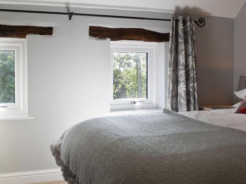 WartonTreacle Cottage - Uk12912的一间卧室设有一张床和两个窗户。