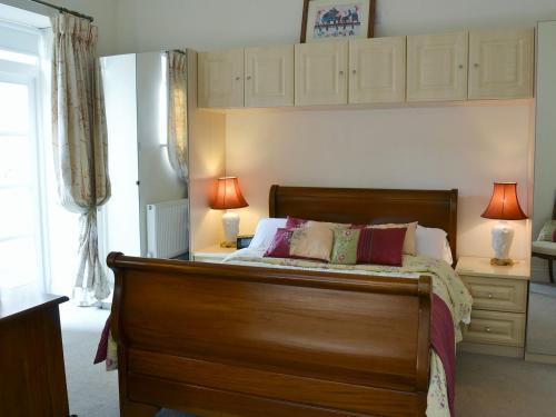 阿克斯明斯特Porters Lodge的一间卧室配有一张木床和两盏灯。