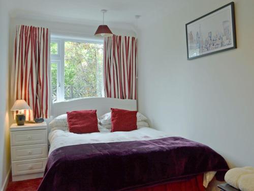 特伦Tigh Beag的一间卧室配有一张带红色枕头的床和一扇窗户