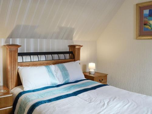 UplawmoorOld Stable Cottage的一间卧室配有一张带木制床头板的床