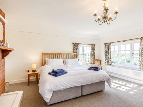 Bradwell on SeaMark Farmhouse的卧室配有一张带吊灯的大型白色床。