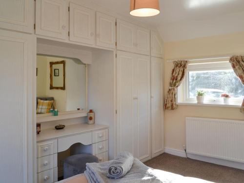 HothamBennys Cottage的一间卧室配有一张床、一张书桌和一个窗户。