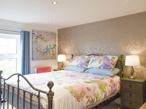米尔登霍尔Beck Cottage的一间卧室配有一张带花卉床罩的床
