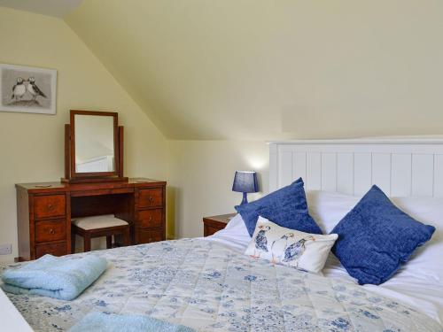 MauchlineThe Brewers Cottage的一间卧室配有一张带蓝色枕头和镜子的床