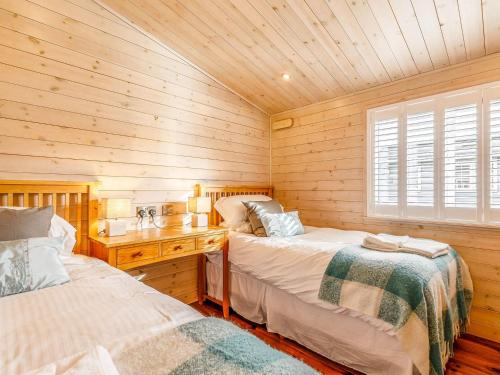 WillingtonWalnut Lodge-uk37595的一间卧室设有两张床和木墙