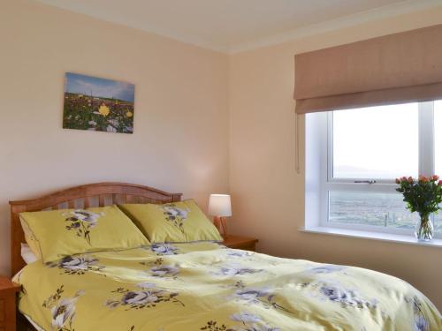 PollacharWest Kilbride的一间卧室配有一张带黄色棉被的床和窗户