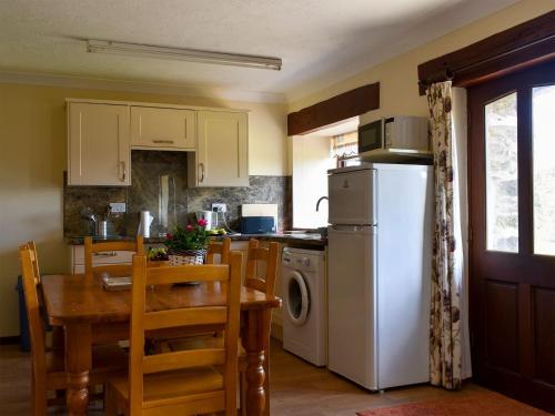 Saint EndellionStable Cottage - Uk12088的厨房配有桌子和白色冰箱。