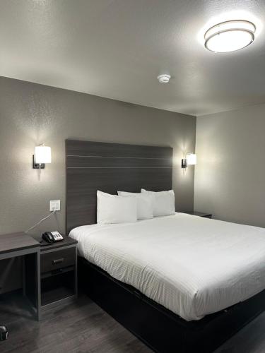 WagonerSleepy Traveler Motel的卧室配有一张带白色床单和枕头的大床。