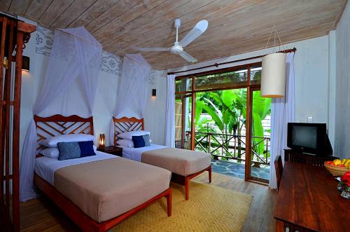 琅勃拉邦梦中精品度假村的一间卧室配有两张床和一台平面电视