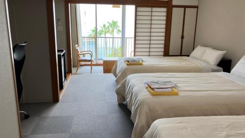 云仙市Obama Onsen Hamakan Hotel的酒店客房设有三张床和阳台