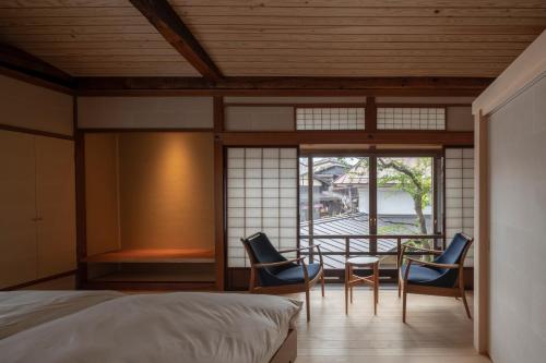 高山TANIYA的一间卧室配有一张床、两把椅子和一张桌子