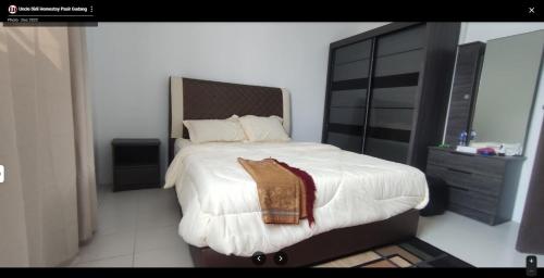 巴西古当Uncle Didi Guest House Pasir Gudang的一间卧室配有一张大床和木制床头板