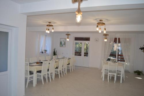 CălăţelePensiunea Anda的一间配备有白色椅子和桌子的用餐室