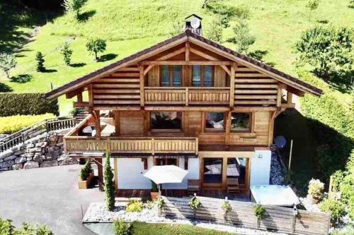 Les Villards-sur-ThônesAndrosace Appartement dans Chalet bois avec Jacuzzi privatif Terrasse et Vue Montagne的一座带绿色山丘的大型木屋