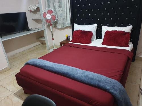 利隆圭House of Joy的一间卧室配有红色的床、红色枕头和风扇