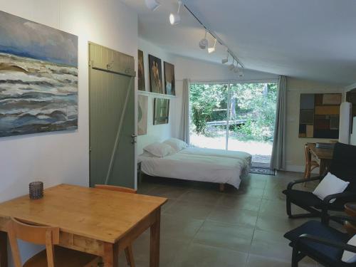 LanetBeautiful studio surrounded by nature的一间卧室配有一张床、一张桌子和一个窗户。