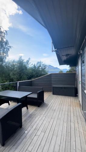 希博滕Strandbu Camping的阳台的木制甲板上配有桌椅
