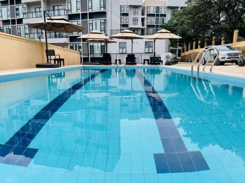 基加利Embassy Access Golf Apartment的一个带椅子和遮阳伞的大型蓝色游泳池