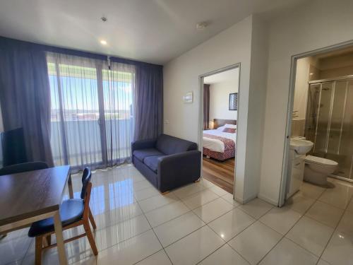 丹德农Exodus Dandenong Apartment Hotel的一间带蓝色沙发的客厅和一间卧室