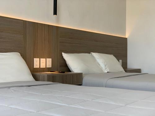 帕丘卡德索托Hotel Blanco Pachuca的一间卧室配有两张带白色床单的床