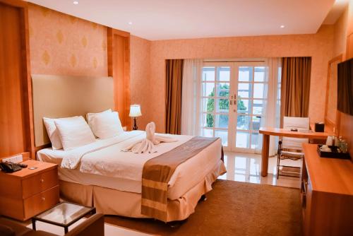 TakengonPortola Grand Renggali Hotel Takengon的配有一张床和一张书桌的酒店客房