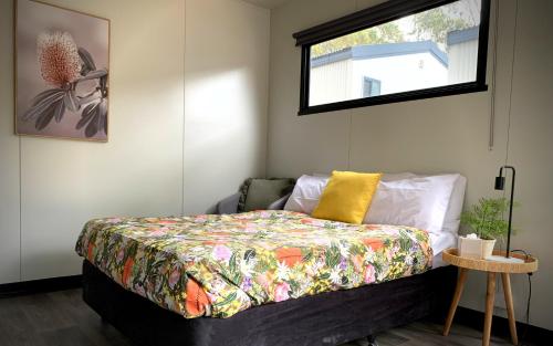 NicholsonLakes Bushland Caravan & Lifestyle Park的一间卧室配有一张带彩色床罩和窗户的床。