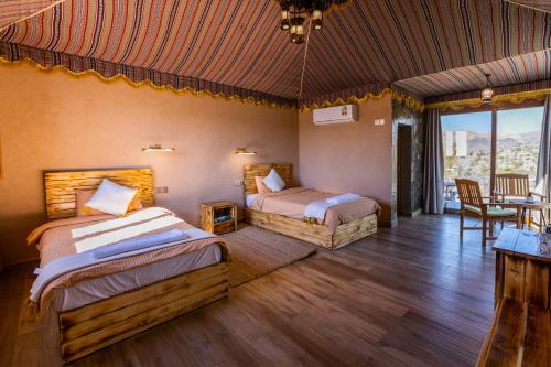 Dār SawdāʼJebel Shams Resort منتجع جبل شمس的一间卧室配有两张床和一张桌子及椅子