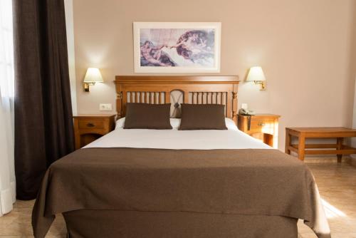 云科斯托莱多卡洛斯I酒店的一间卧室配有一张大床和两张桌子