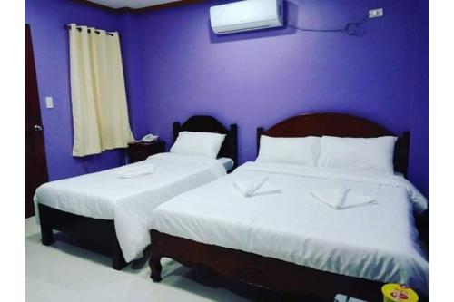 长滩岛OYO 926 Casa Venicia Caticlan的卧室设有两张床铺和紫色墙壁