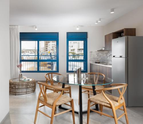 耶路撒冷AMALON Boutique Apartments的厨房配有玻璃桌、椅子和冰箱