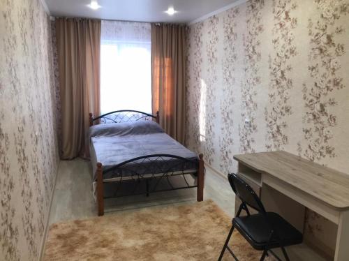 乌斯季卡缅诺戈尔斯克Lux Home на Амурской的一间卧室配有一张床、一张书桌和一个窗户。