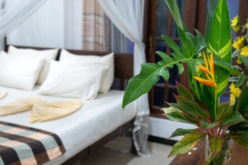 乌纳瓦图纳Villa Sunimal的一间卧室配有带白色枕头和植物的床