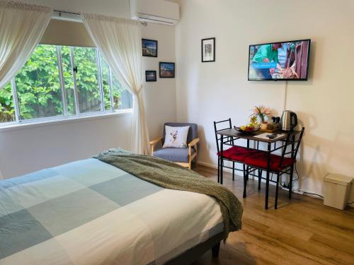 尤姆迪Eumundi Cottage in Town的一间卧室配有一张床、一张桌子和一个窗户。