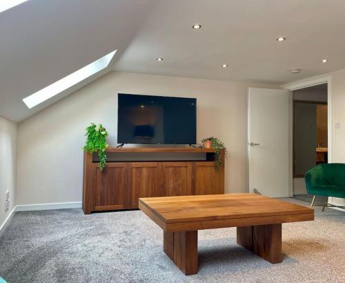 StewartonVennel Street Apartments的客厅配有桌子和平面电视。