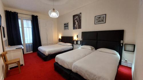 埃维昂莱班帕莱斯酒店的酒店客房,设有两张床,铺有红地毯。