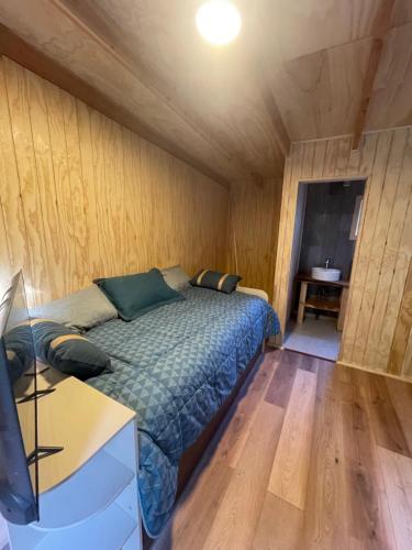 卡斯特鲁Tiny house los zorzales的卧室配有一张床铺,位于带木墙的房间内